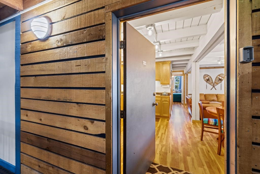 Corridor featuring beamed ceiling, light wood-type flooring, and wooden walls