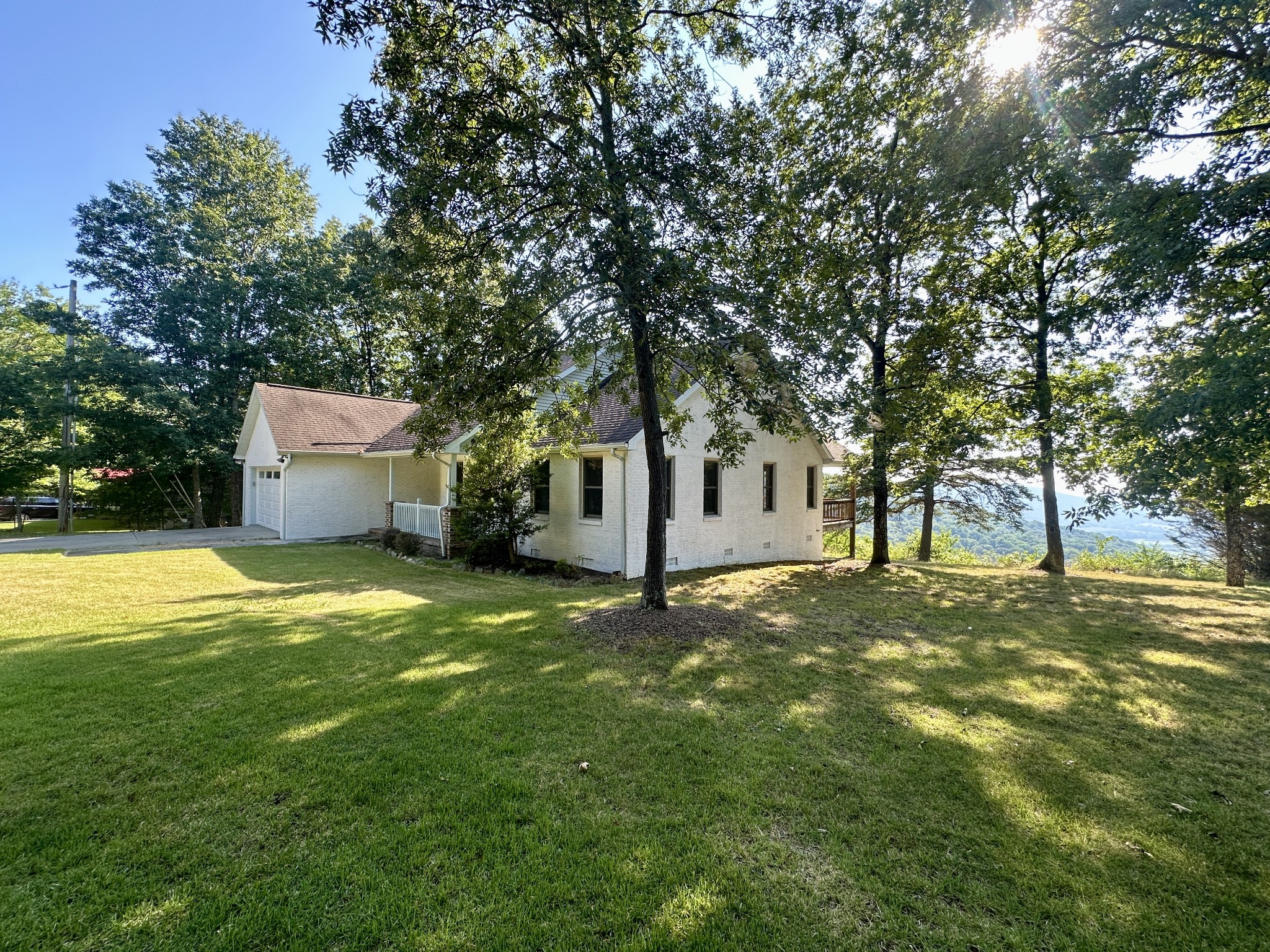 a view of a white house with a yard and large tree