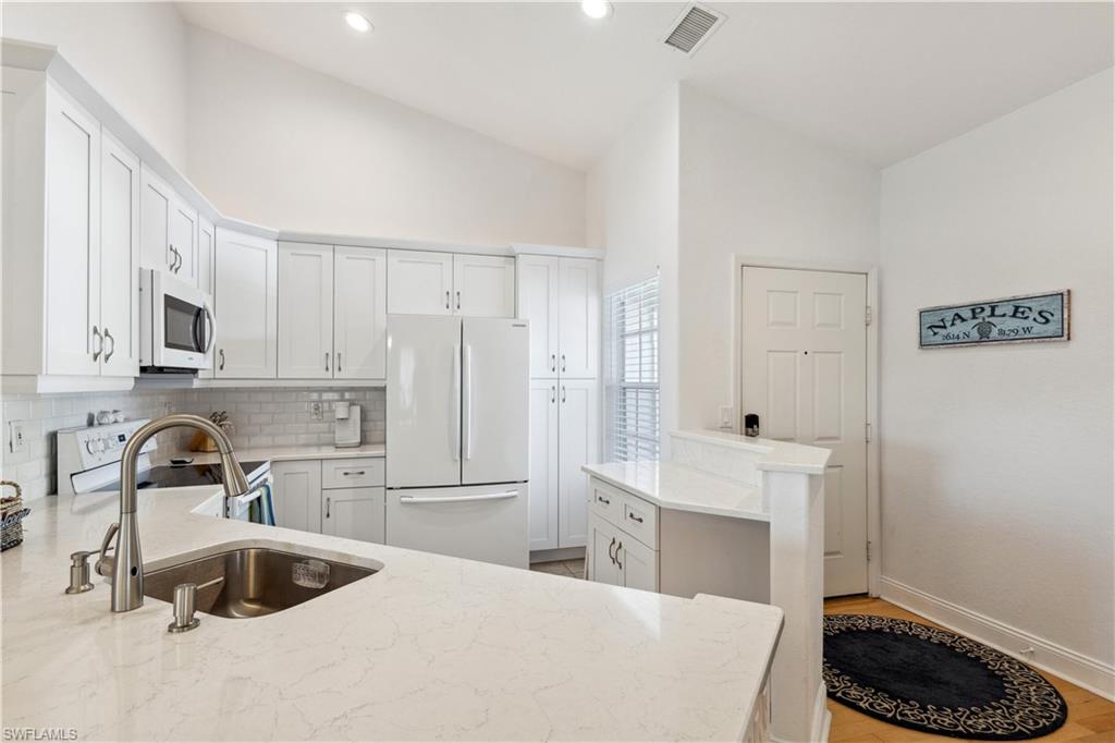 a kitchen with granite countertop a sink a stove and refrigerator