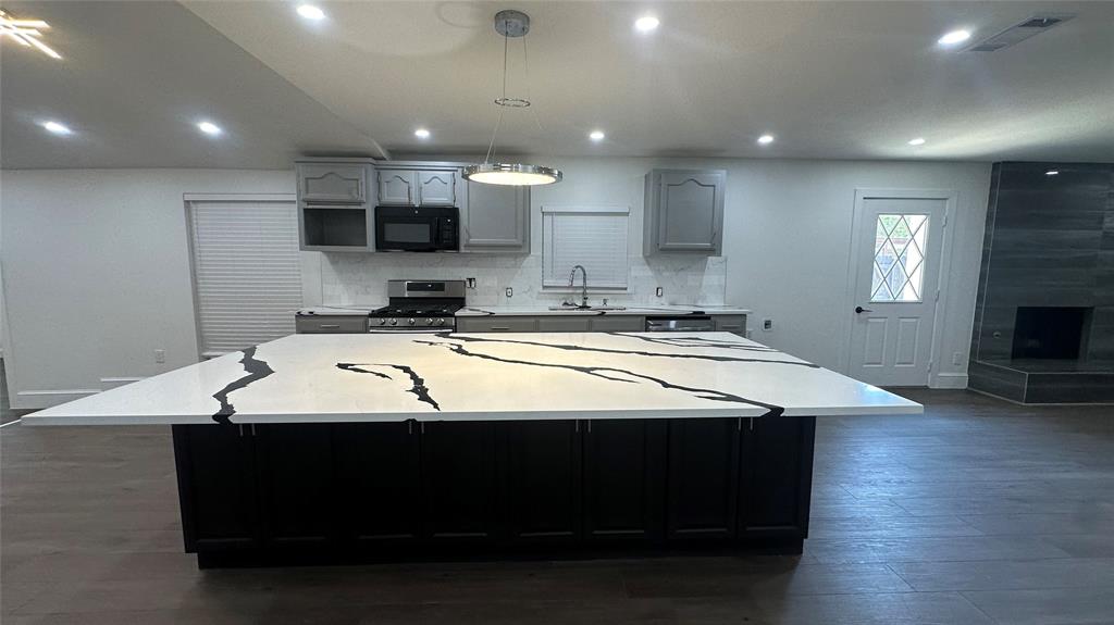 a room with kitchen island stainless steel appliances sink cabinets and wooden floor