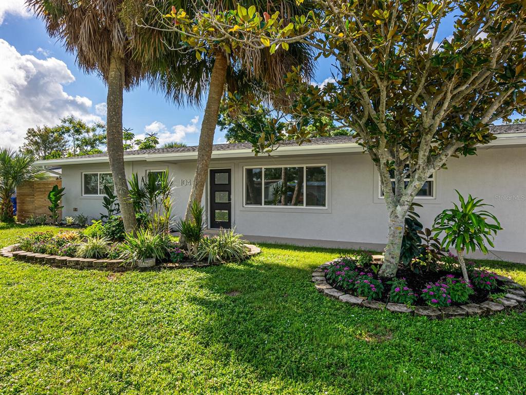 a front view of a house with a yard and potted plants