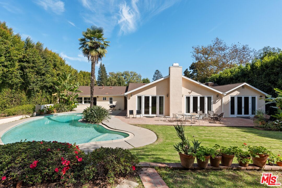 a front view of a house with a garden and trees