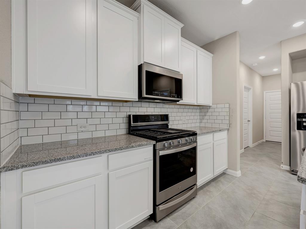 a kitchen with granite countertop white cabinets and stainless steel appliances