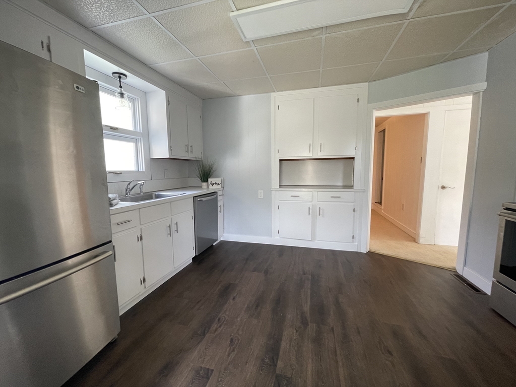 a kitchen with a refrigerator a sink dishwasher with a fireplace and wooden floor