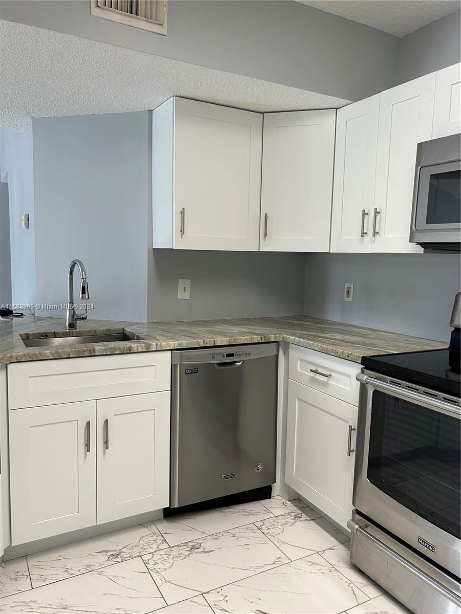 a kitchen with granite countertop white cabinets and white appliances