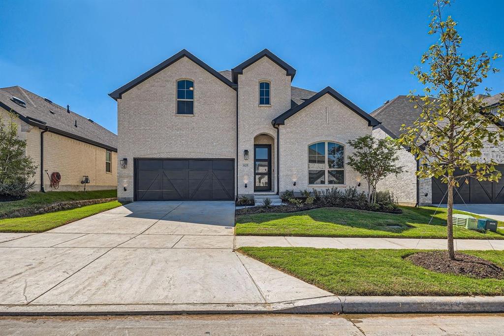 French provincial home featuring a garage and a front lawn