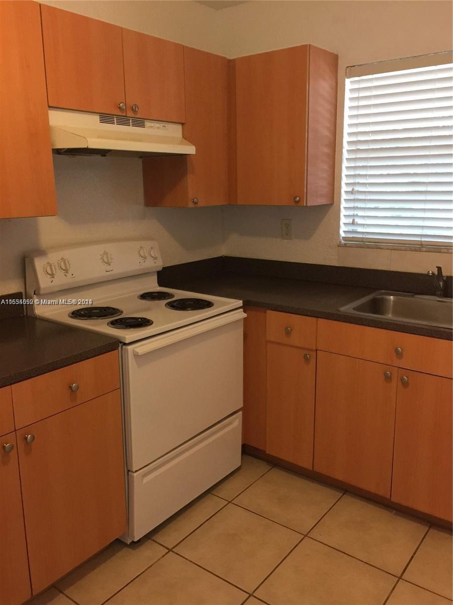 a kitchen with granite countertop a sink stove and cabinets