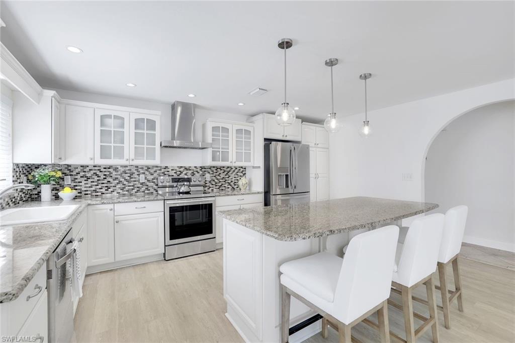 a kitchen with stainless steel appliances granite countertop a kitchen island a stove a table and chairs