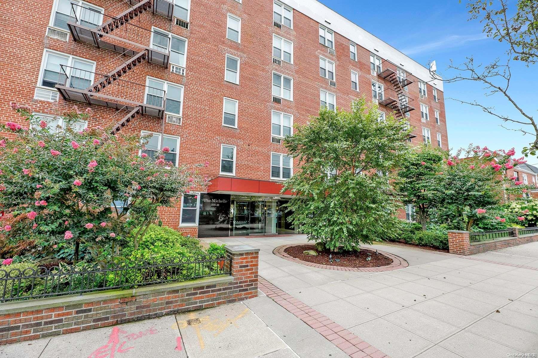 a front view of a multi story residential apartment building with yard and bench