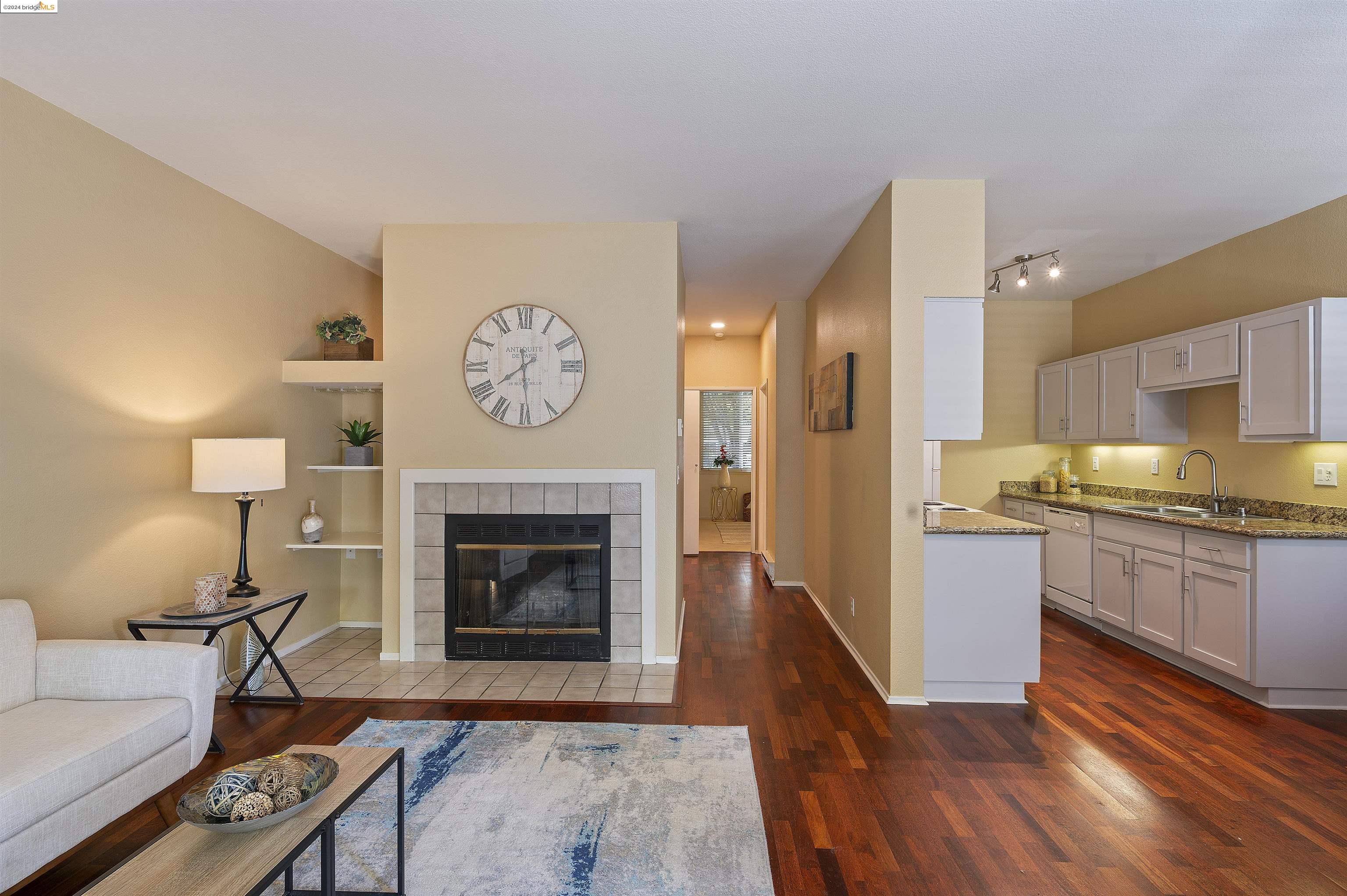 a living room with stainless steel appliances granite countertop furniture a fireplace a rug and a window