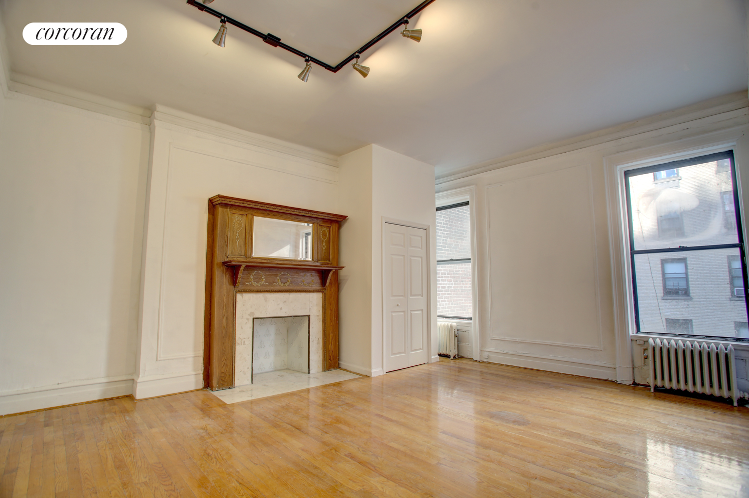 a view of an empty room with wooden floor and a window