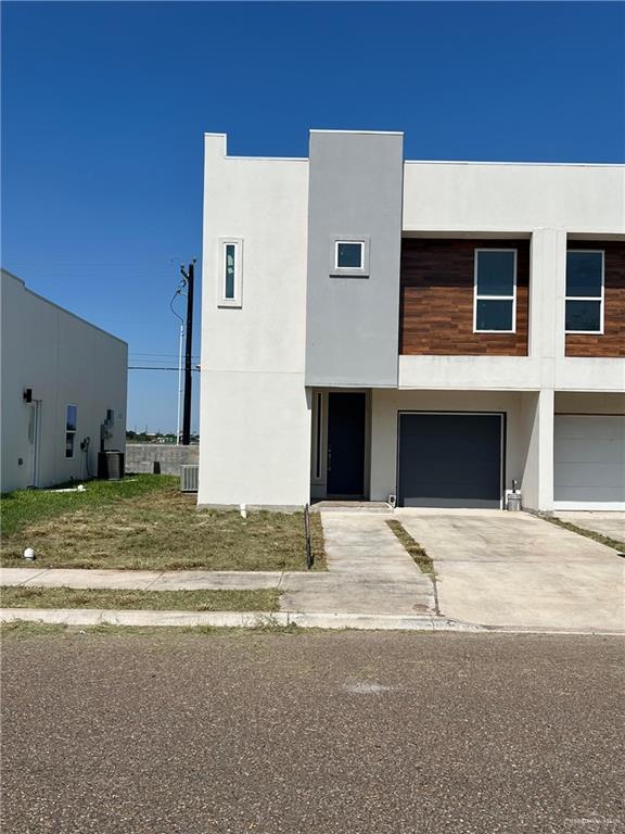 View of front facade featuring a garage and cooling unit