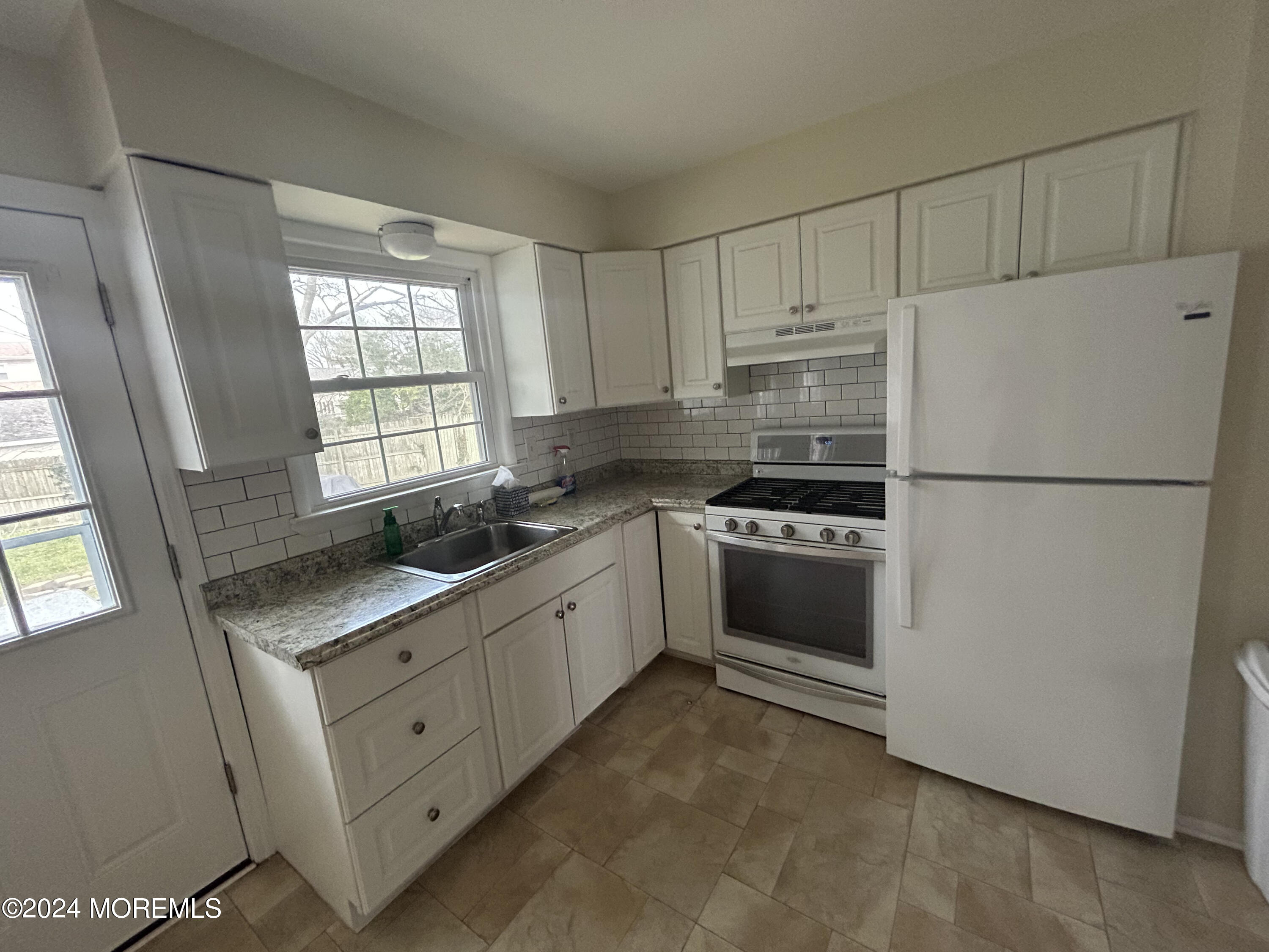 a kitchen with granite countertop white cabinets and white appliances