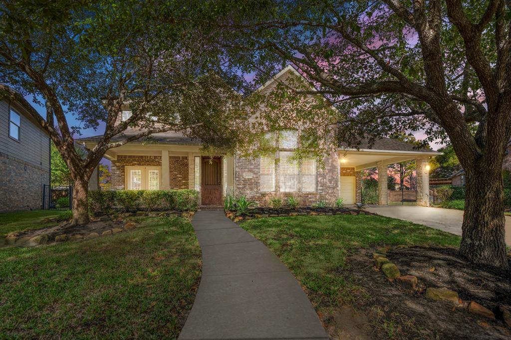 a front view of a house with a yard and large trees