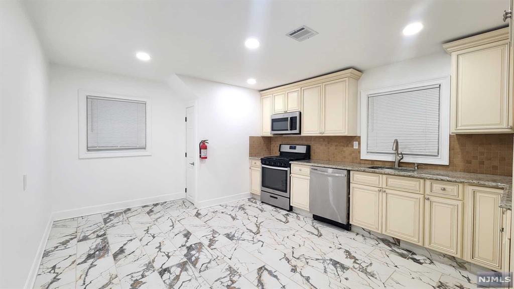 a kitchen with granite countertop a sink cabinets and stainless steel appliances