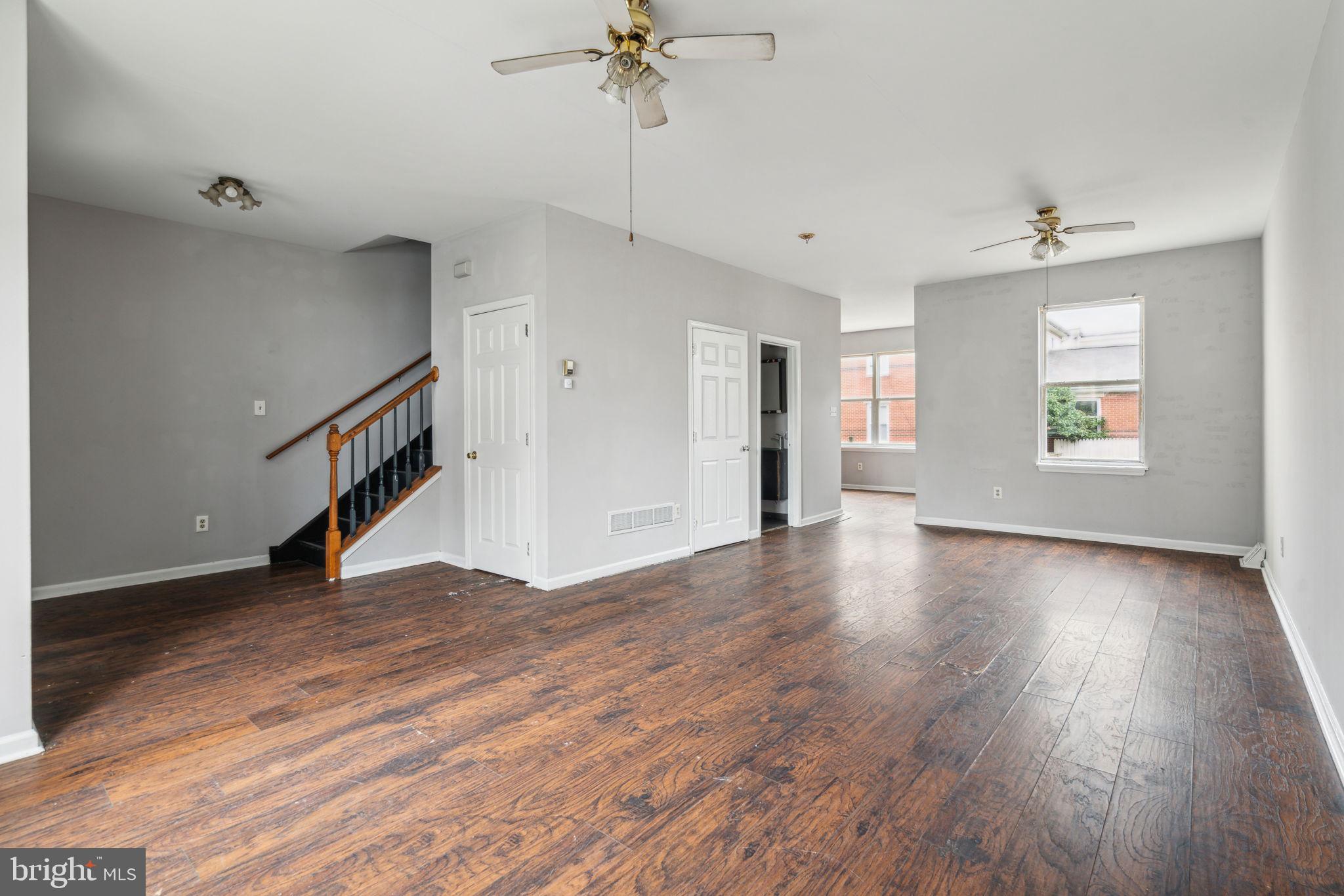 a view of an empty room with window and wooden floor