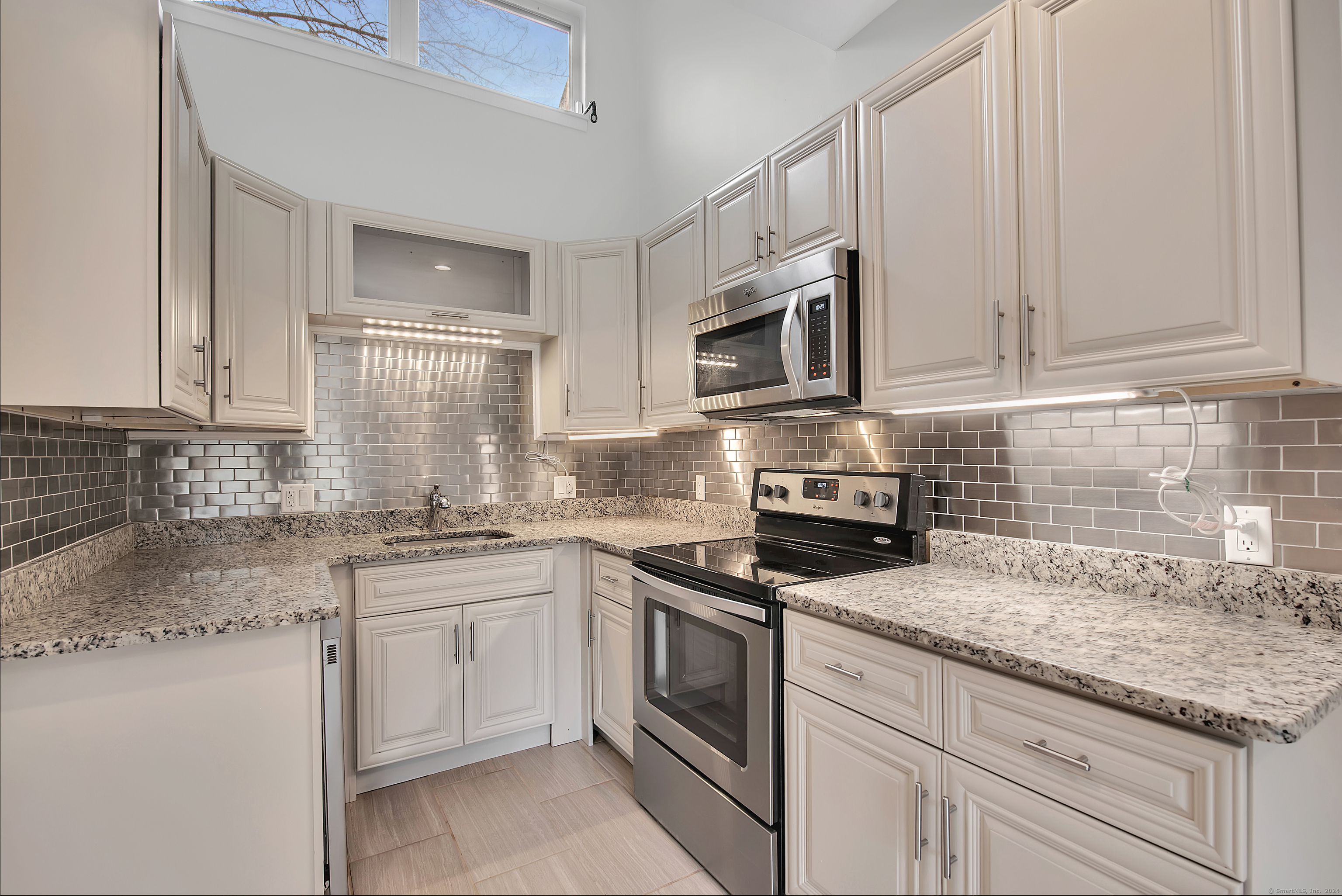 a kitchen with granite countertop white cabinets white stainless steel appliances with a sink and dishwasher