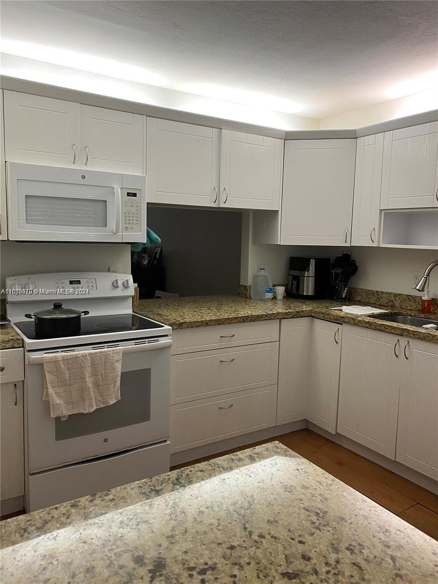 a kitchen with granite countertop a stove sink and cabinets