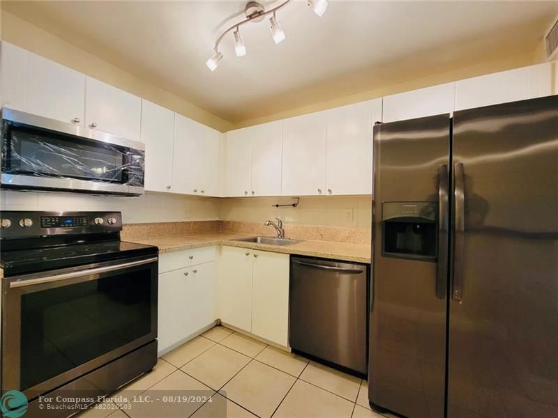 a kitchen with stainless steel appliances granite countertop a refrigerator a stove and a sink with wooden floor