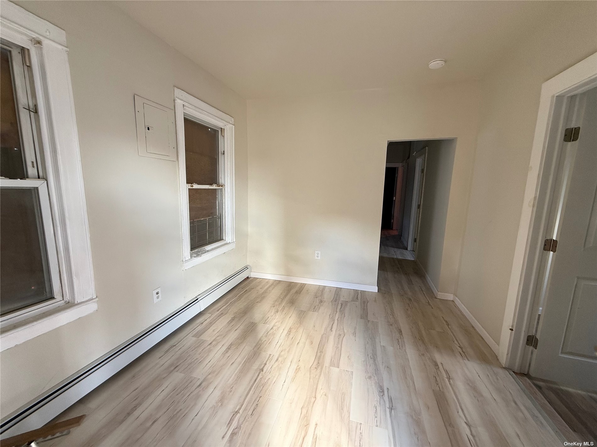 a view of an empty room with wooden floor and a window