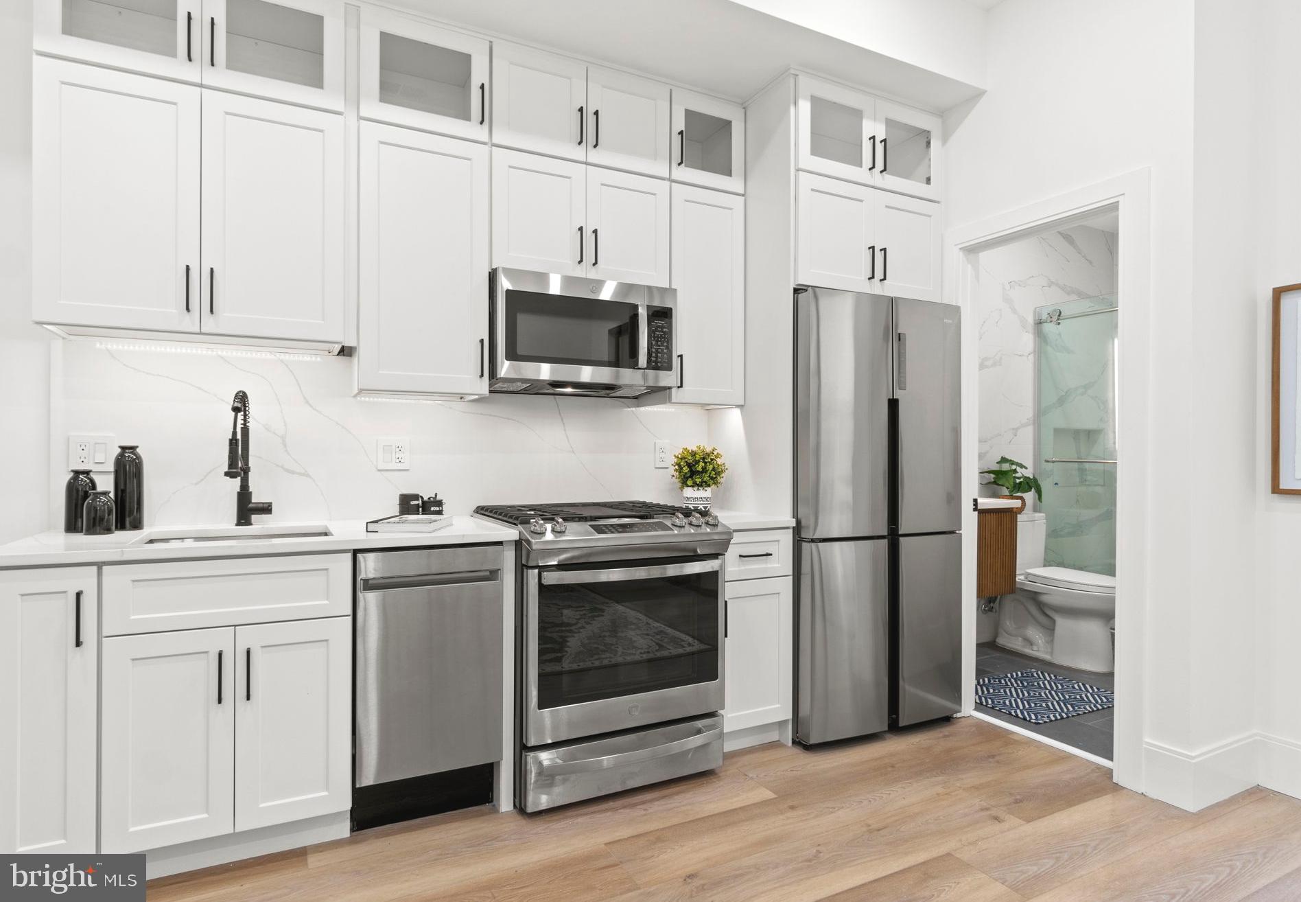 a kitchen with cabinets stainless steel appliances and wooden floor