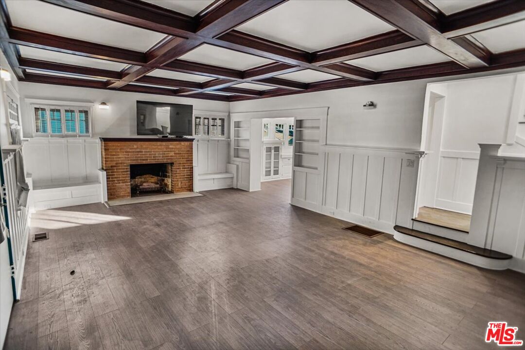 a view of an empty room with wooden floor a fireplace and windows