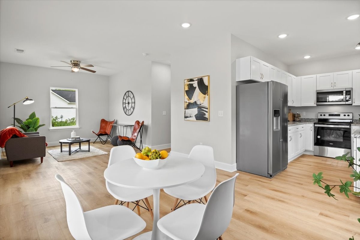a open kitchen with stainless steel appliances furniture dining table and wooden floor