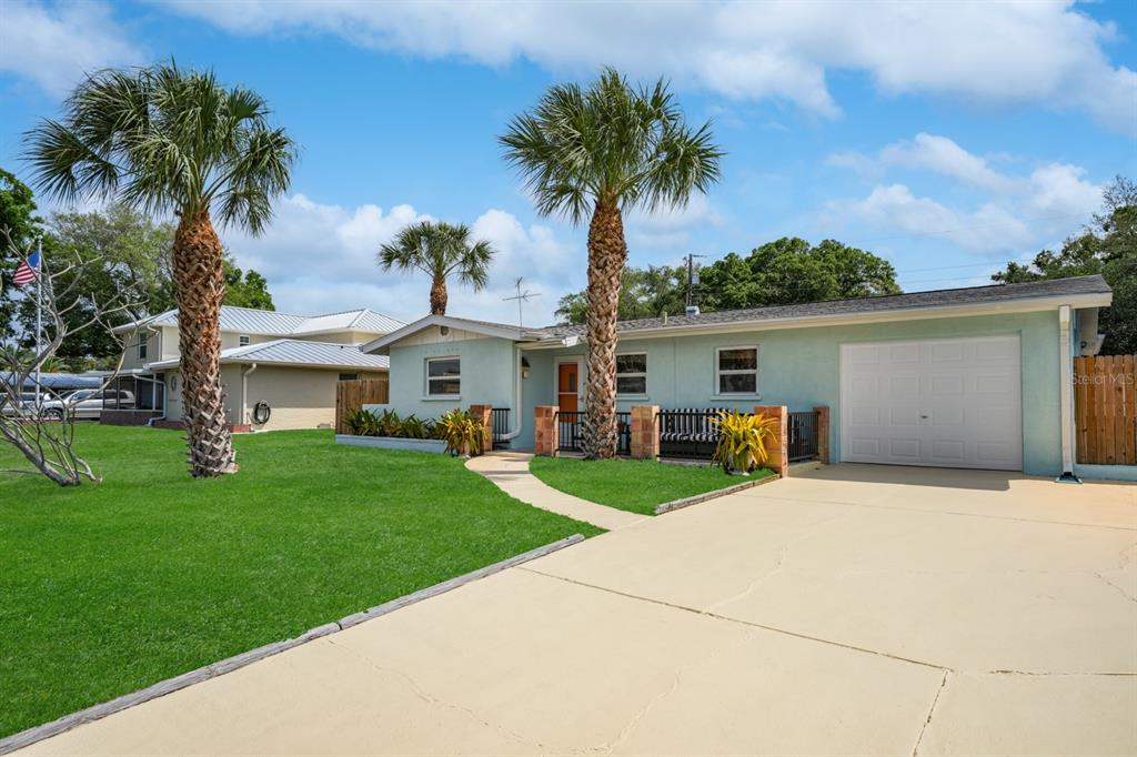 a view of a house with a yard and palm trees