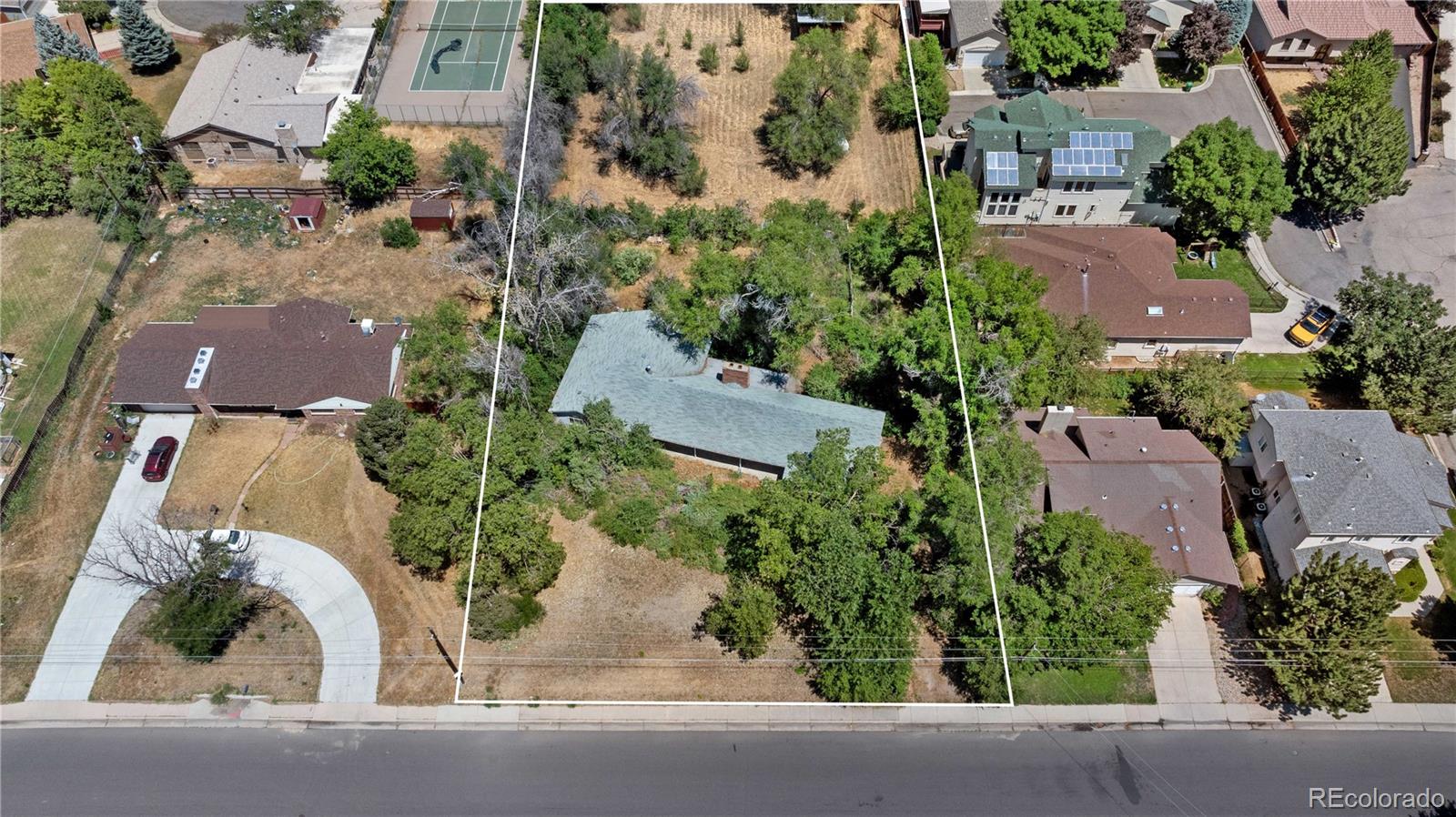 an aerial view of a house with a yard and a car park side of road