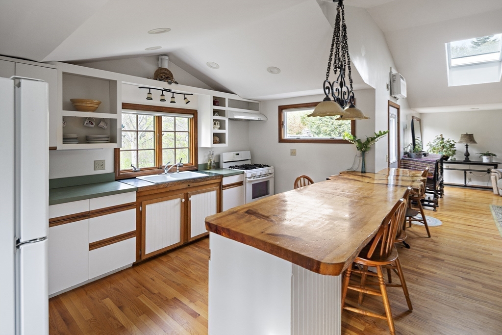 a kitchen with stainless steel appliances kitchen island granite countertop wooden floor and window