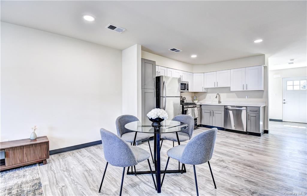 a kitchen with stainless steel appliances kitchen island hardwood floor and chairs