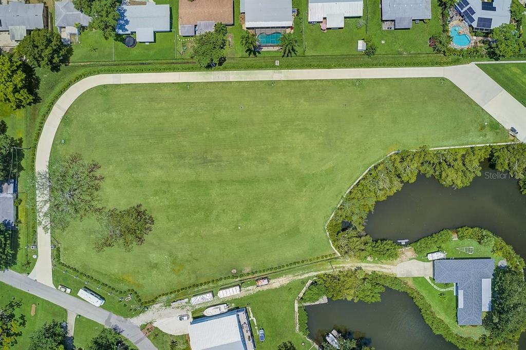 an aerial view of a residential houses with outdoor space and a lake view