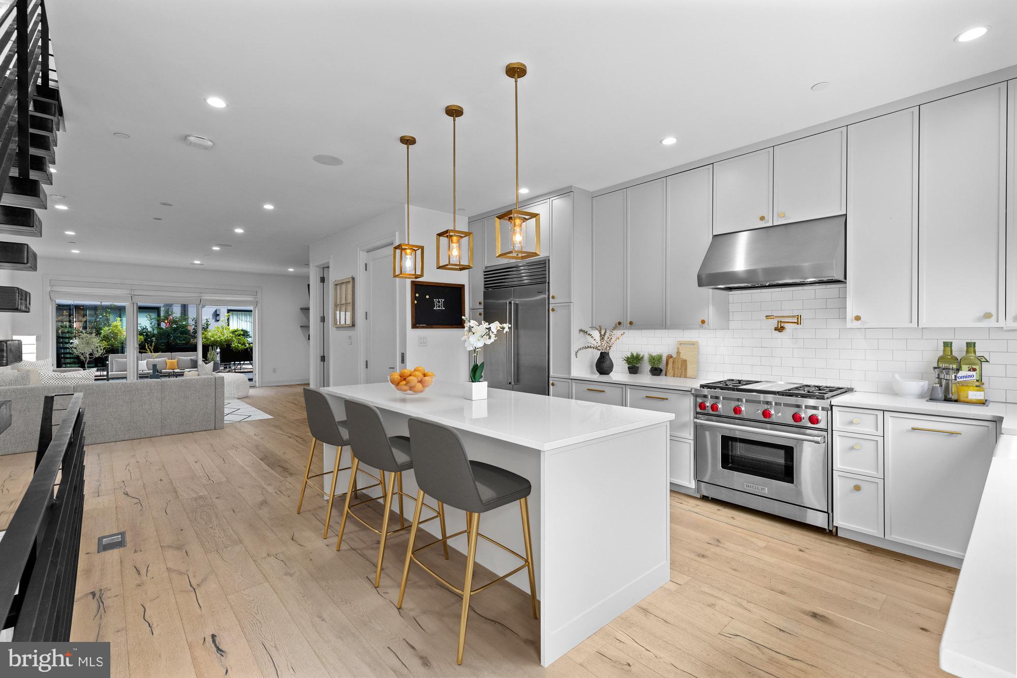 a kitchen with stainless steel appliances kitchen island granite countertop a stove a sink a microwave a refrigerator and white cabinets with wooden floor