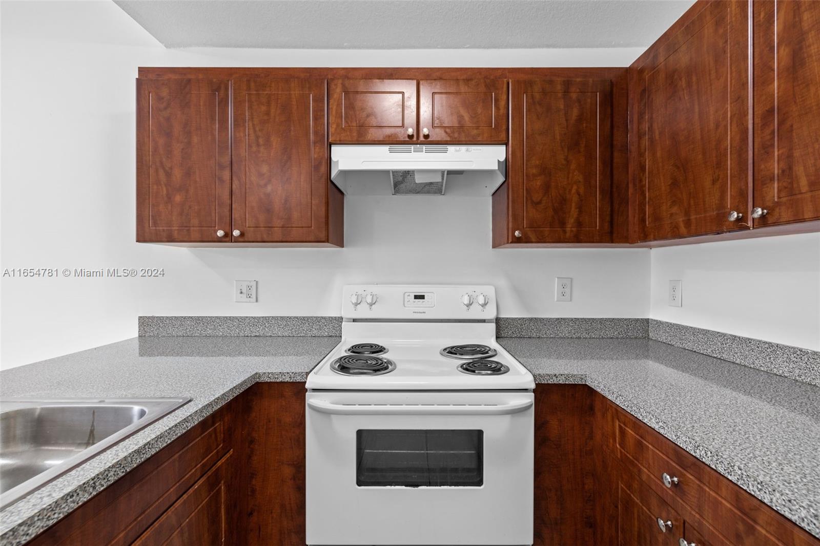 a kitchen with granite countertop wood cabinets and white appliances