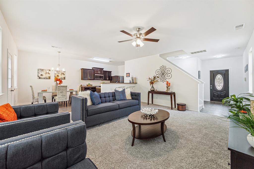 a living room with furniture a rug and a ceiling fan