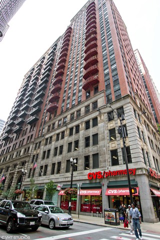 a front view of a building with lot of cars and trees