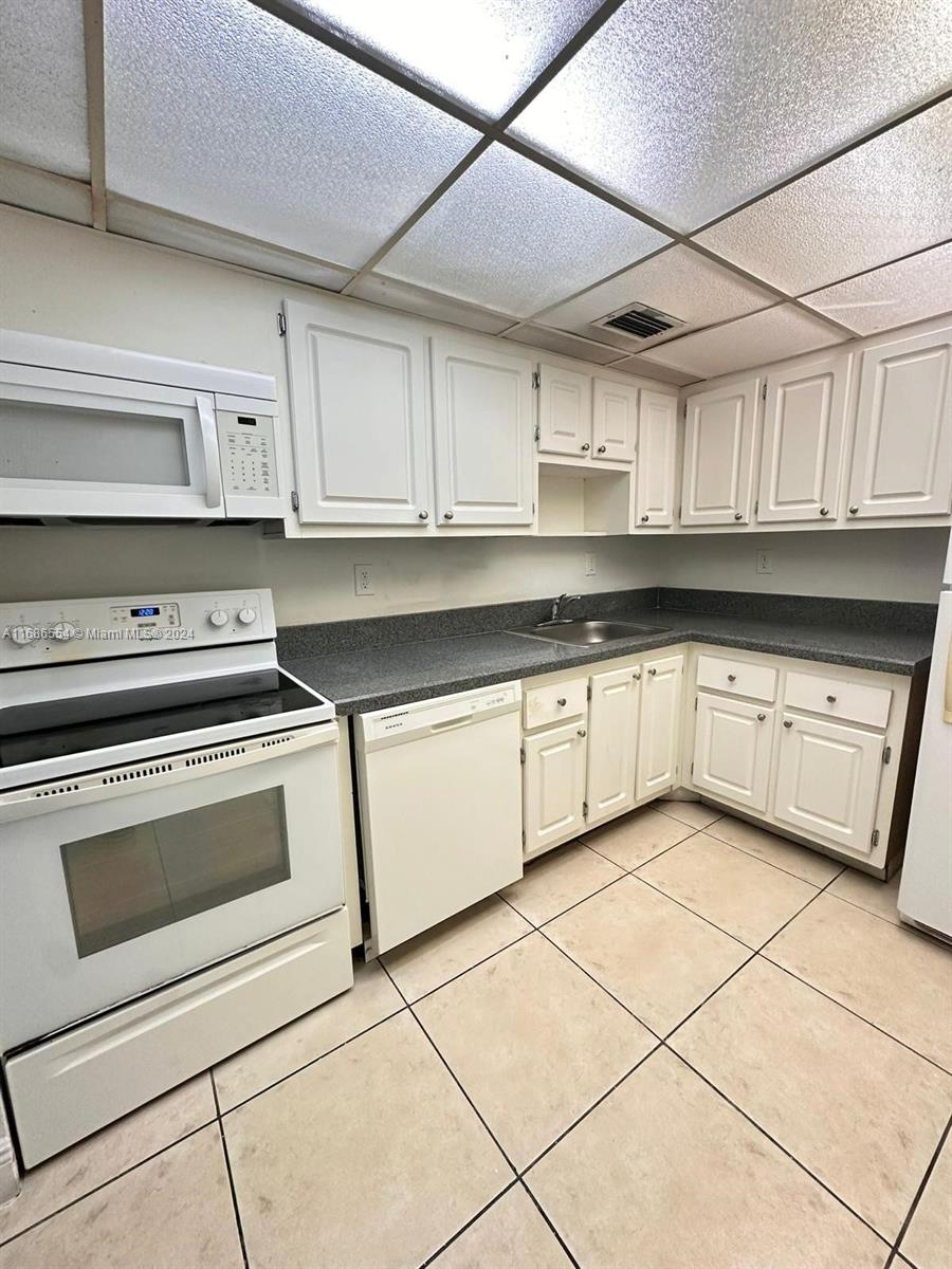 a kitchen with granite countertop white cabinets stainless steel appliances and a sink