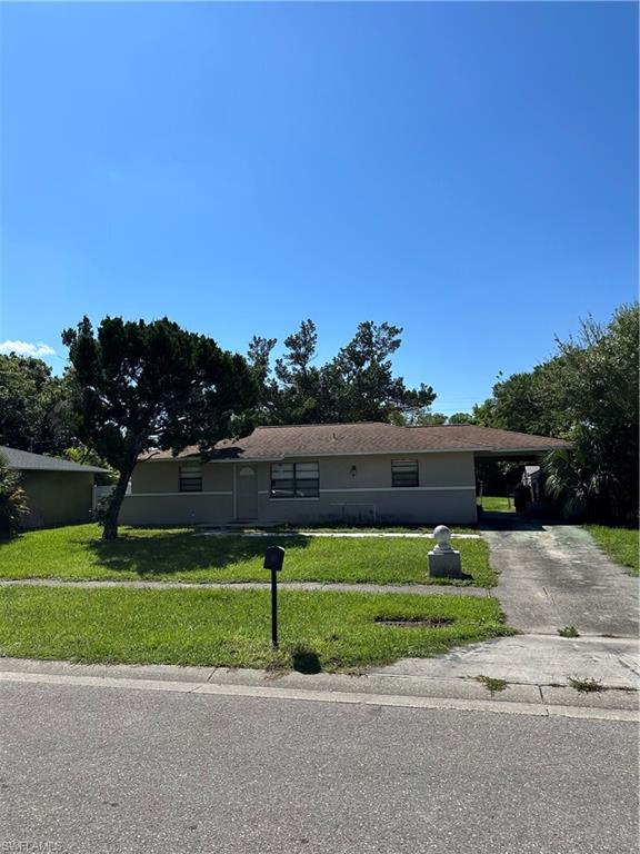 View of front of property featuring a front lawn and a carport