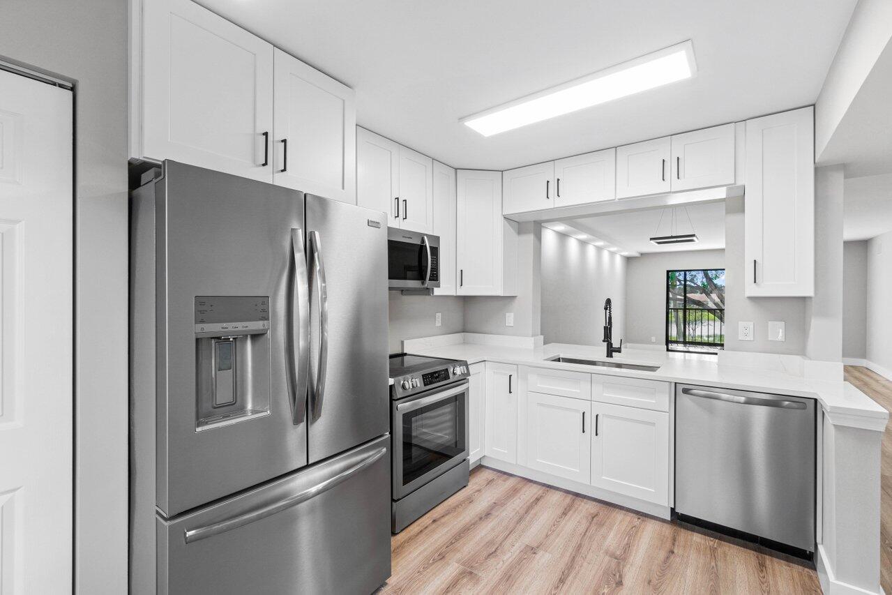 a kitchen with stainless steel appliances a refrigerator stove and white cabinets