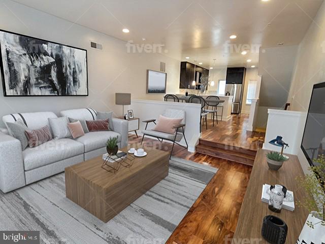 a living room with furniture kitchen view and a wooden floor