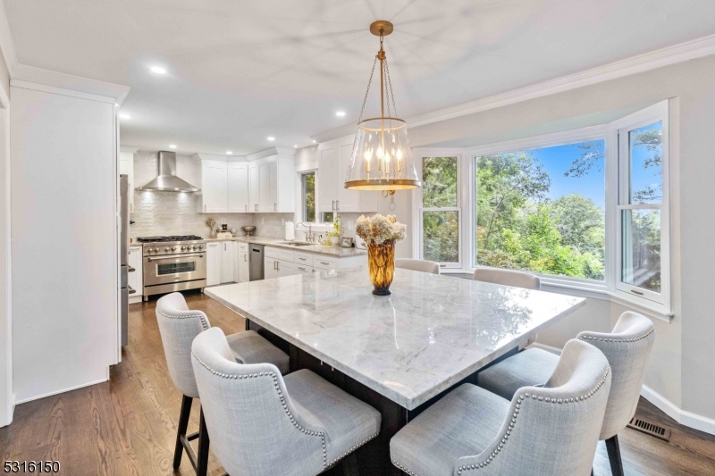 a dining room with stainless steel appliances furniture a large window and a kitchen view