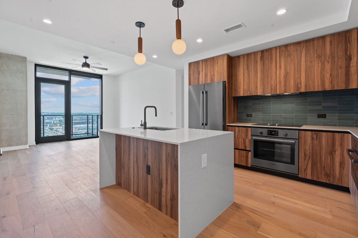 a kitchen with kitchen island granite countertop wooden cabinets a sink and a stove