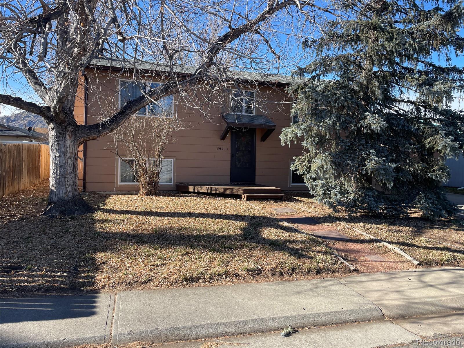 a view of a house with a small yard and large tree