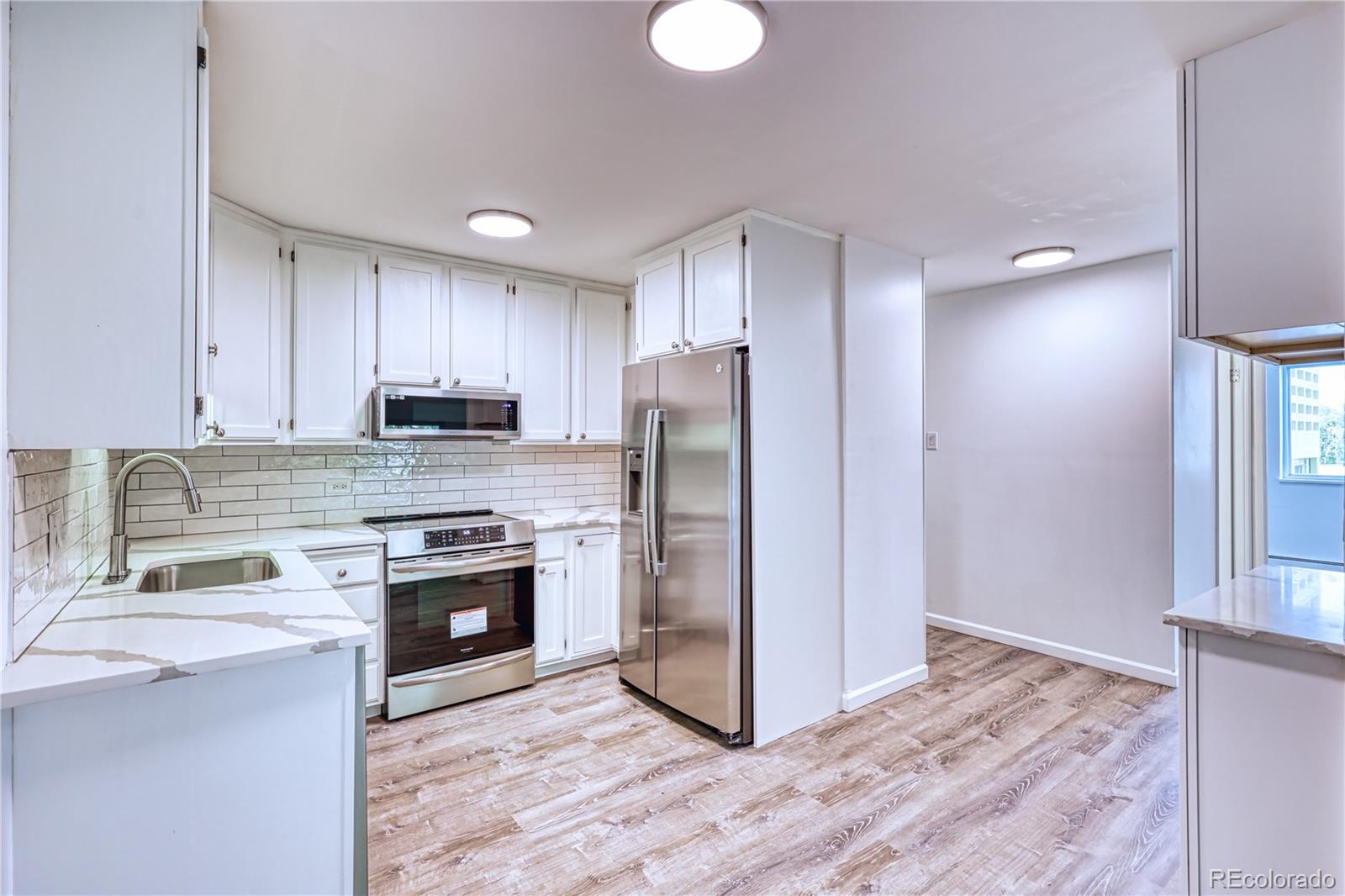 a kitchen with granite countertop a stove top oven and refrigerator