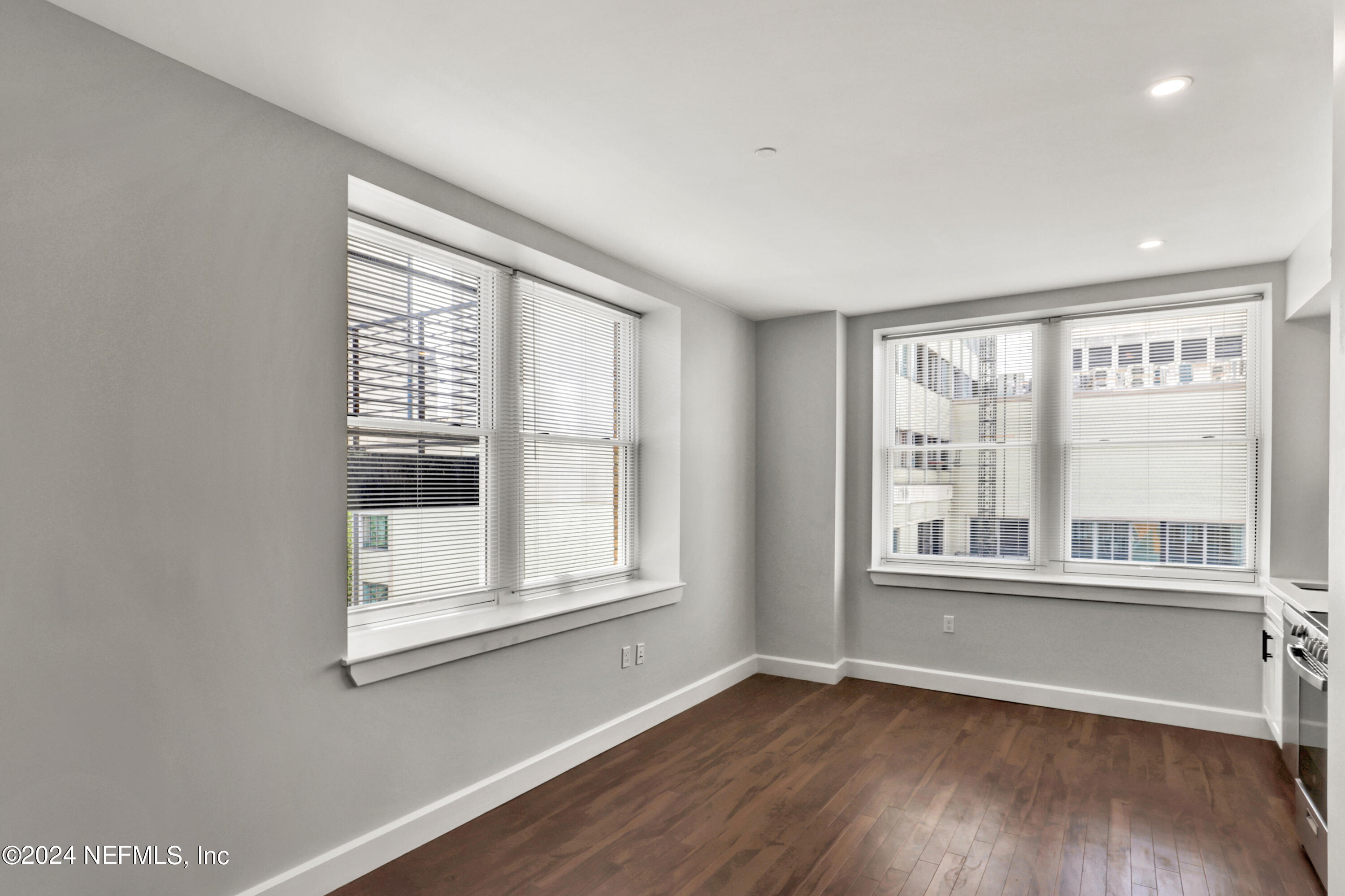 an empty room with wooden floor and windows