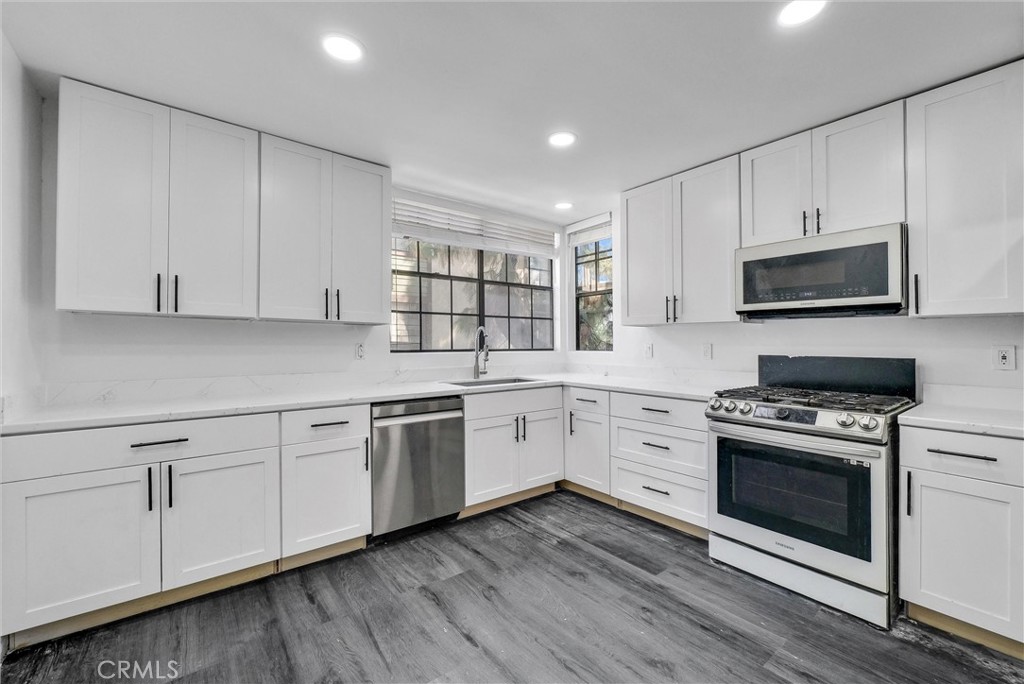 a kitchen with cabinets stainless steel appliances and wooden floor