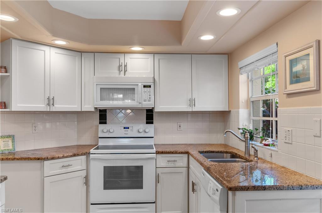 a kitchen with granite countertop white cabinets and white appliances