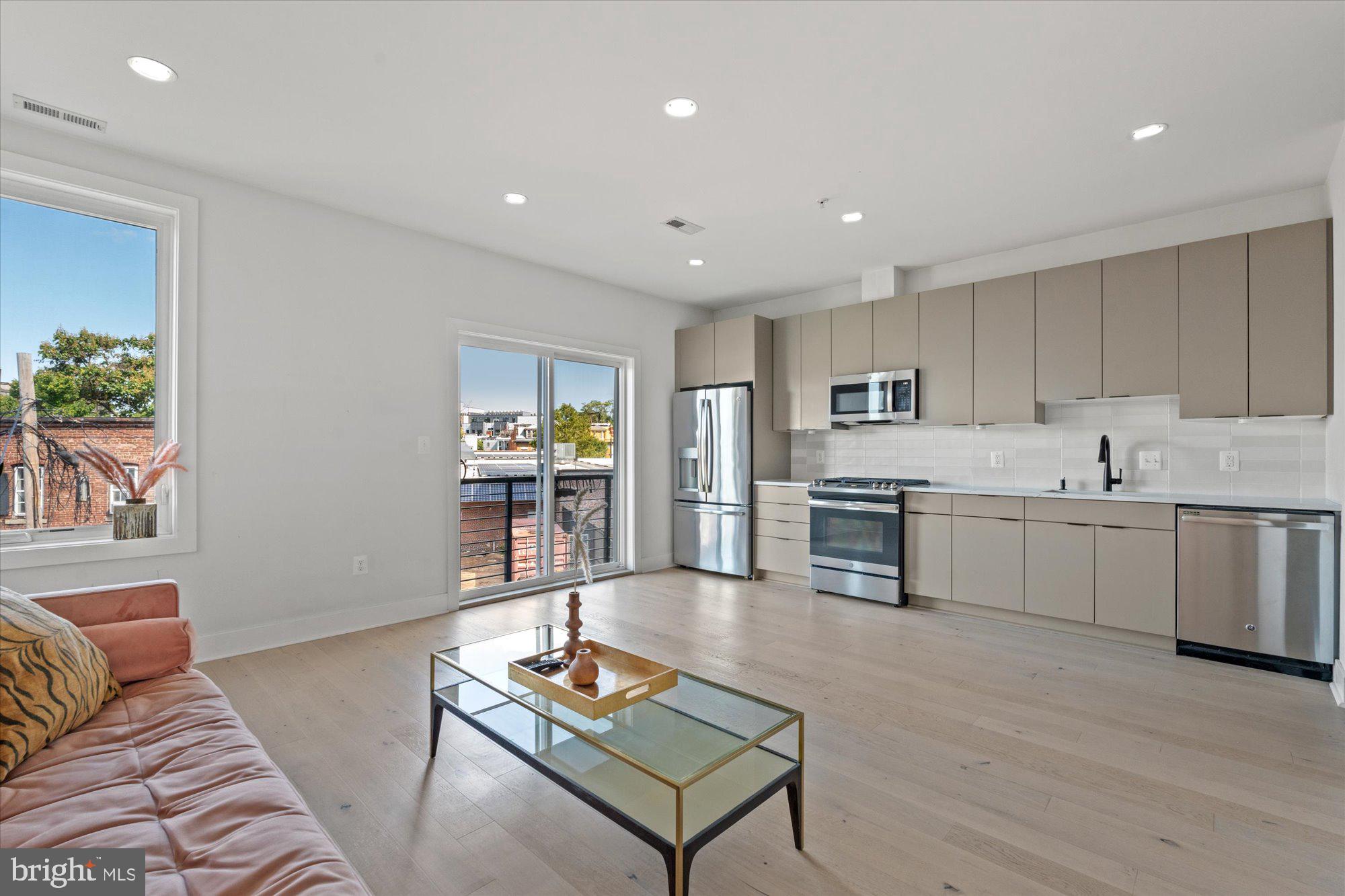 a living room with stainless steel appliances kitchen island granite countertop furniture and a wooden floor