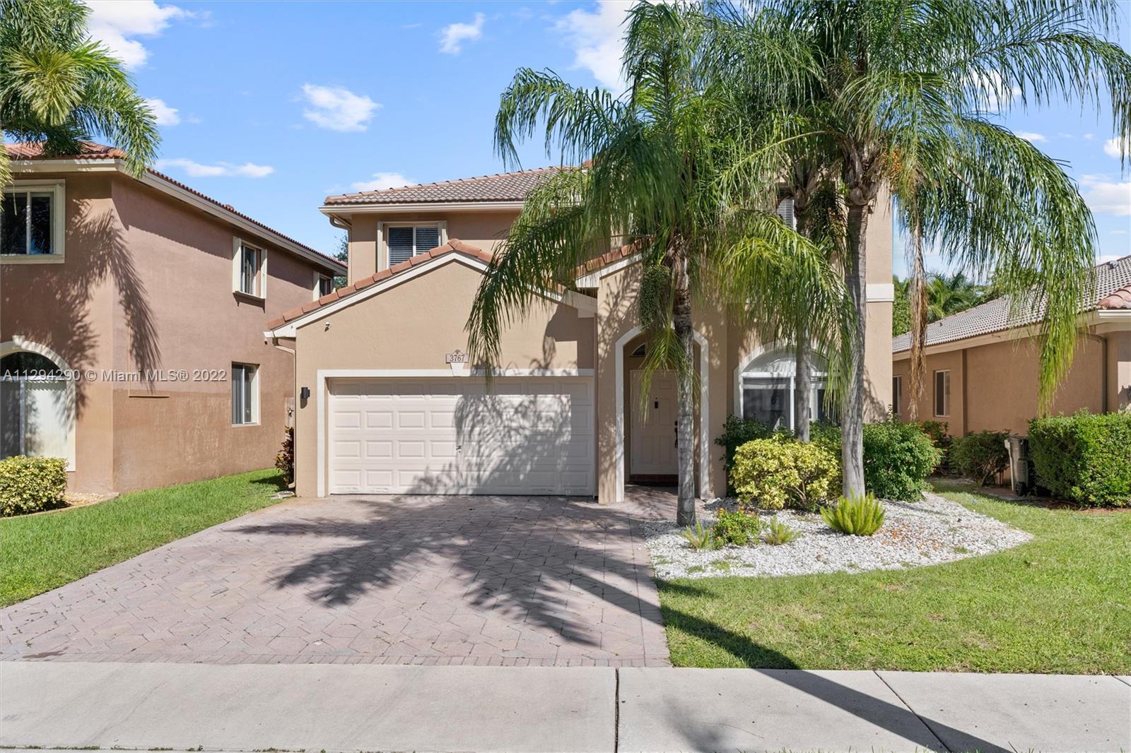 front view of house with a yard and palm trees