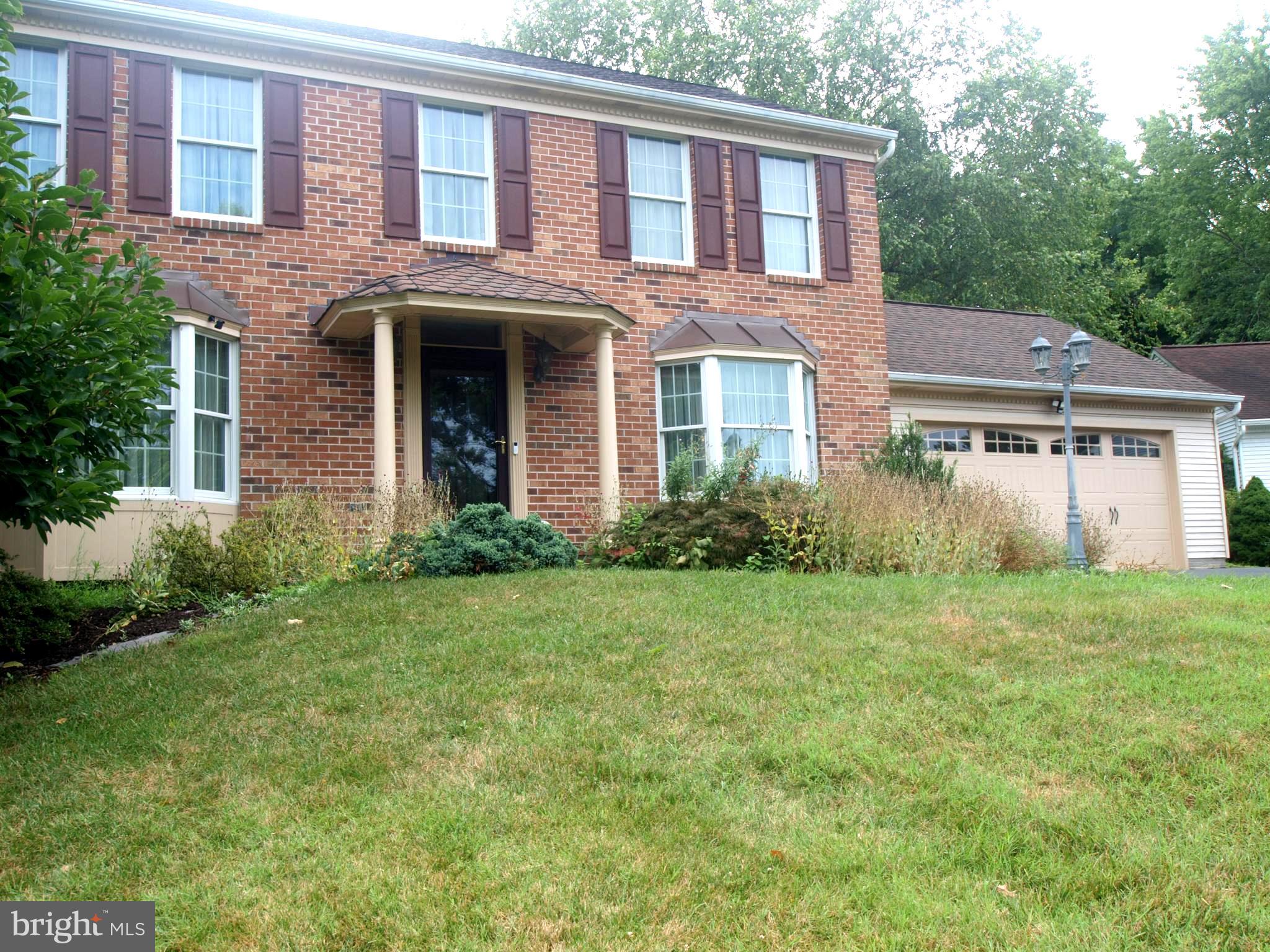 a view of a brick house with a yard and large trees